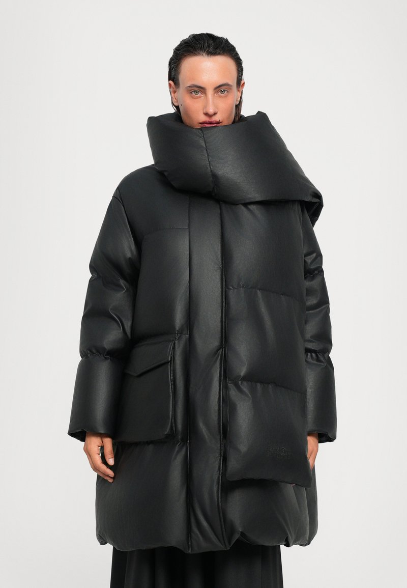 Μαύρο μπουφάν τύπου puffer με ψηλό γιακά, υπερμεγέθη σιλουέ�τα, γυαλιστερή υφή και μπροστινή τσέπη. Διαθέτει φαρδιά μανίκια και επενδυμένο σχέδιο.