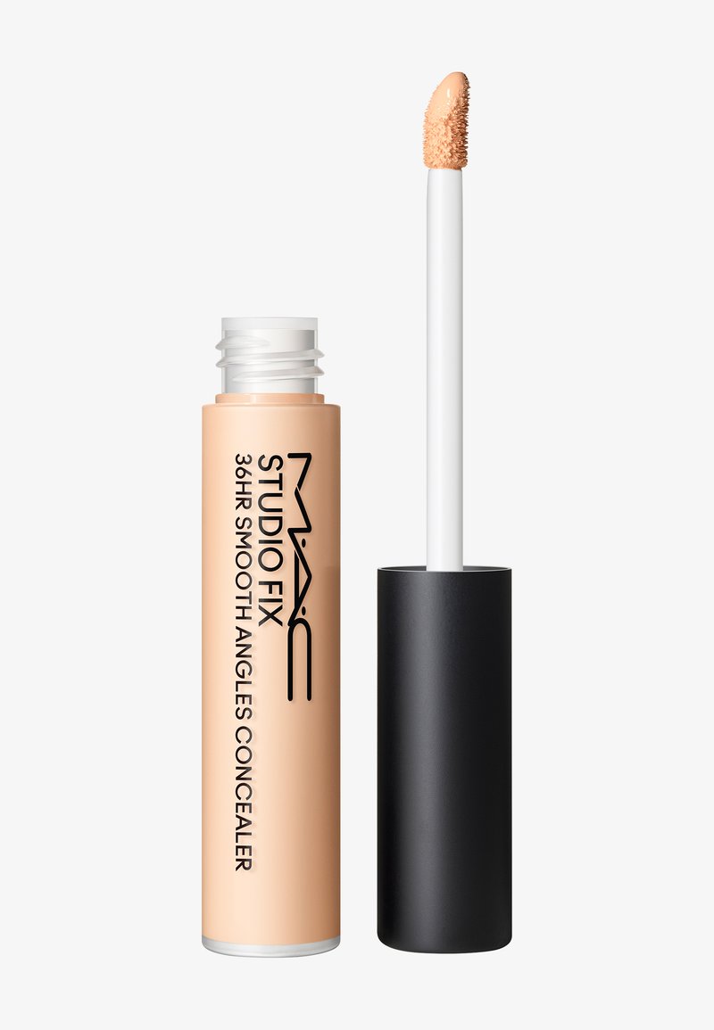 Tube de correcteur étiqueté MAC Studio Fix 36HR Smooth Angles avec un capuchon noir et une baguette applicatrice montrant du produit beige au bout.