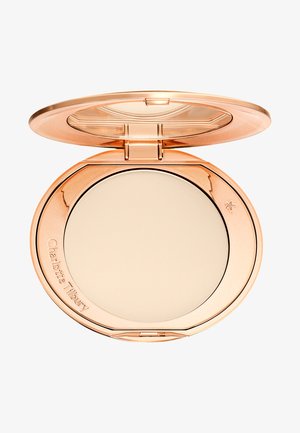 Compact powder in a rose gold case with a transparent lid, featuring a smooth beige powder surface and embossed brand name.