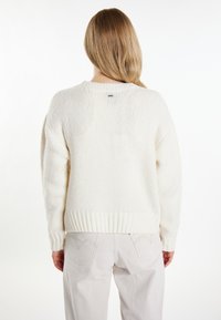 Crème kleurige gebreide sweater met geribde zoom en manchetten. Zachte textuur met een relaxte fit en ronde halslijn, zicht op de achterkant.