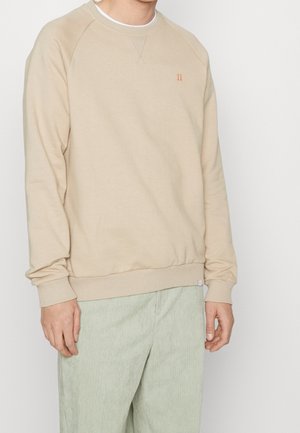 Beige sweatshirt met ronde hals en raglan mouwen, met ribgebreide manchetten en onderrand. Heeft een klein oranje logo op de borst. Gemaakt van een zachte katoenmix.
