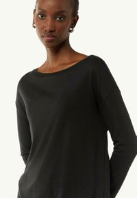 Zwart longsleeve shirt met een brede, ronde halslijn, een losse pasvorm en een zachte textuur. Beschikt over verlaagde schouders en naadloze manchetten.