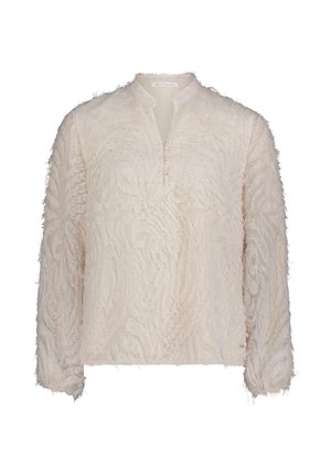 Kremowa bluzka z długim rękawem o teksturowanej, frędzlowanej powierzchni. Posiada kołnierz z wycięciem i trzy ozdobne guziki z przodu.