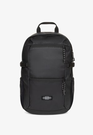 Mochila negra de tela resistente, con un bolsillo delantero con cremallera, correas laterales ajustables y un asa superior para facilitar su transporte.