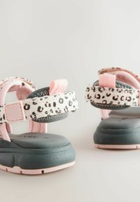Vaaleanpunaiset ja leopardikuvioiset sandaalit, joissa on pehmustettu harmaa pohja, säädettävä hihna ja teksturoitu kangas, jossa on kontrastiväriset tikkausdetailit.
