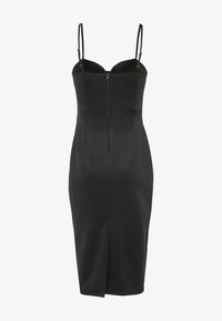 Svart figurnära klänning med tunna axelremmar, hjärtformad linning, blixtlås i ryggen och en sprund vid mitten av låret. Slät textur och kroppsnära design.