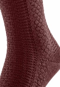 Calzino bordeaux con texture e motivo a coste, caratterizzato da un design lavorato a maglia. Il materiale sembra morbido ed elastico, adattandosi alla forma del piede.