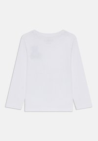 Langärmliges weißes Baumwoll-T-Shirt mit Rundhalsausschnitt, das einen kleinen schwachen Fleck auf dem Stoff aufweist, mit geradem Saum und ohne weitere Designs.