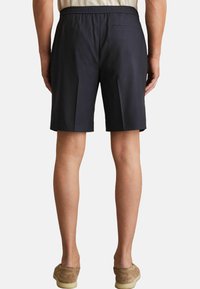Shorts de culoare albastru marin cu față plată, talie elastică și un singur buzunar pe spate. Materialul pare neted și are o croială ajustată.