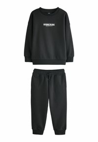 Sort sæt bestående af sweatshirt og joggers lavet af blødt stof. Sweatshirten har hvid "SUBSCRIBE" tekst; joggers har elastisk talje og manchetter.