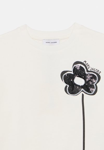 Λευκό φούτερ με σχεδιασμό λουλουδιού από μαύρες παγιέτες, που διαθέτει έναν βλαστό και το όνομα της μάρκας "MARC JACOBS" σε κυρτό κείμενο.
