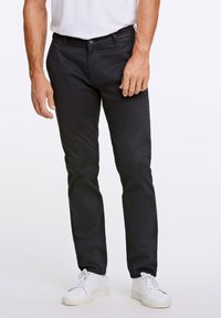 Czarne chinosy wykonane z bawełny w fasonie slim fit, z zapięciem na guzik i zamek błyskawiczny, paskiem z pętlami oraz kieszeniami bocznymi. W połączeniu z białymi sneakersami.