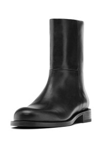 Bottine en cuir noir, avec un bout rond, une texture lisse, un petit talon empilé et un design minimaliste. Pas de matériel ou de motifs visibles.