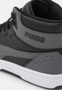 Baskets montantes noires et grises en cuir et matériaux synthétiques, avec le logo PUMA, des détails de couture, et une semelle blanche.