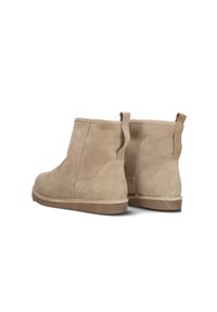 Beige suède enkellaarzen met een gladde textuur, elastische zijpanelen en trekriemen aan de achterkant. Dikke rubberen zolen zorgen voor stabiliteit.