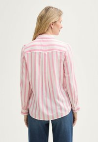 Pikad varrukad, roosad ja valged triibulised särgid, millel on nööpidega mansetid, tagumine õlavarras ja ümardatud äär, sobitatud siniste teksapükstega.