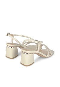 Crème-kleurige hoge sandalen met een vierkante neus, slanke banden en blokhakken met chroomaccenten voor extra detail.