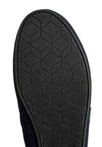 Suela de zapato de goma negra con un patrón texturizado de panal, que presenta un borde ligeramente elevado y una parte superior de ante oscuro y suave.