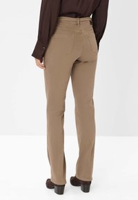 Pantaloni dritti color tan realizzati in tessuto morbido, con due tasche posteriori e vita alta. Abbinati a stivali neri con tacco.