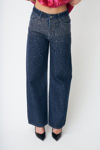 Tamsiai mėlynos spalvos džinsai plačiomis kojomis, dekoruoti išsklaidytomis sidabrinėmis kniedėmis, su klasikiniu penkių kišenių dizainu ir sagos užsegimu.