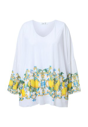 White tunic with a V-neck and wide sleeves. Features a vibrant yellow lemon and floral pattern along the hem. Smooth, lightweight fabric.