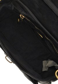 Interno di una borsa a mano in pelle nera con fodera in tessuto scuro, cerniera in tono oro e un piccolo cartellino visibile in basso. Il design è semplice e funzionale.