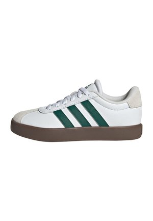 Witte lage sneaker met donkergroene strepen, bruine zool, witte veters en een beige suède neuskap en hielstuk.