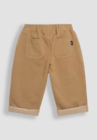 Pantalons en coton marron clair avec taille élastique, deux poches arrière et ourlets à revers, présentant un détail de tissu texturé.