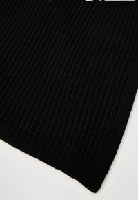 Tuva tuvumā melna ribota adīta auduma ar vertikālām faktūru līnijām uz baltas fona.