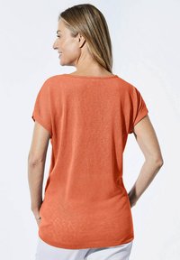 Korte mouwen oranje T-shirt met een relaxte pasvorm, ronde halslijn en zachte textuur. De achterkant toont gladde naden en een iets langere zoom.