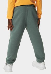 Grønne sweatpants med en afslappet pasform, lavet af blødt materiale. Har en elastisk talje og manchetter, designet til komfort og bevægelsesfrihed.