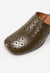 Chaussure slip-on en cuir perforé vert olive avec un bout rond, présentant une finition brillante et une doublure intérieure lisse.