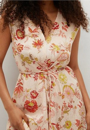 Sukienka w kwiatowy wzór w jasno-beżowym kolorze z czerwonymi, różowymi i zielonymi kwiatami. Posiada dekolt w kształcie litery V, talię zebranej w pasie oraz miękki materiał.