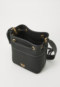 Μαύρη δερμάτινη τσάντα με σχήμα κουβά, με χρυσά σκληρά στοιχεία, λευκές ραφές και κλείσιμο με κορδόνι. Διαθέτει ρυθμιζόμενο λουρί ώμου.