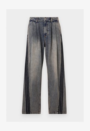 Jean en denim gris délavé taille haute avec des plis et des rayures verticales noires le long des côtés extérieurs de chaque jambe.