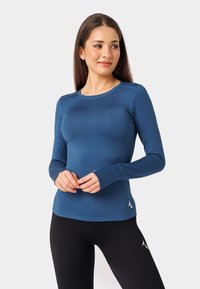 Zils garām piedurknēm sporta tops, izgatavots no stiepjamā auduma, ar apaļu kakla izgriezumu, pirkstu caurumiem un diskrētu logo detaļu pie apakšmala.