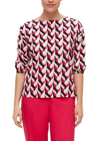 Blouse à motifs présentant un design en chevrons noir, blanc et rose, avec un col bateau et des manches roulées, fabriquée en tissu léger et doux.