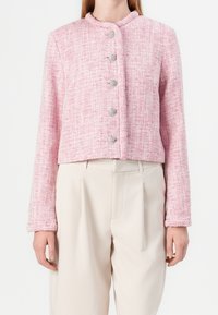 Růžový tweedový krátký kabátek s kulatým límcem, s pěti stříbrnými knoflíky vpředu a texturovanou tkaninou ve vzoru rybí kosti.