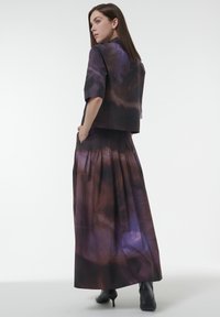 Cropped black and purple tie-dye jacket paired with a long, pleated skirt; both made of smooth fabric with a flowy texture.