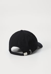 Casquette de baseball noire en tissu texturé, avec une visière courbée, une sangle réglable à l'arrière et du matériel en métal argenté.