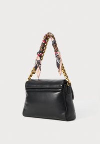 Bolso de mano de cuero negro con forma redondeada, que cuenta con una correa de cadena dorada envuelta en acentos de tela colorida. Incluye un cierre superior con cremallera.