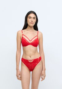 Punane pitsiline pesu комплект, mis sisaldab rinnahoidjat kuldsete detailidega ja peente rihmadega, ning sobivaid kõrge vöökoha aluspükse keerukate lillemotiividega.