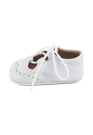 Zapato de bebé de cuero blanco con detalles perforados de brogue y cordones atados, suela blanda, visto de lado sobre fondo blanco.