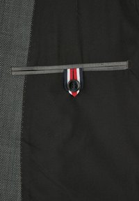 Schwarzer Stoff mit einem strukturierten grauen Muster, ausgestattet mit einer mit Knöpfen versehenen Tasche, die einen gestreiften Akzent in Rot, Weiß und Blau aufweist.