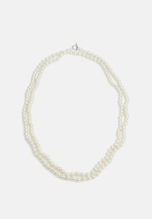Collier de perles blanches à double rangée avec des perles sphériques et un petit fermoir en argent sur un fond blanc uni.