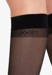 Schwarze Strumpfstrümpfe bis zur Oberschenkelmit einem transparenten Finish. Der gerippte obere Bund zeigt den Markennamen "JOOP!" in einem dezenten, grauen Farbton. Glatte Textur.