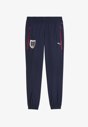 Pantalon de sport bleu marine avec fermetures éclair rouges sur les poches, taille et poignets élastiques, logo de l'équipe de football d'Autriche sur la gauche, logo Puma sur la cuisse droite.