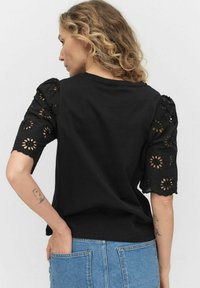 Czarna koszulka z haftowanymi krótkimi rękawami w kwiatowe wzory, uzupełniona luźnym krojem i okrągłym dekoltem.