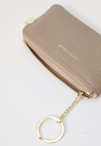 Light taupe leather wallet with a textured finish, gold zipper, and a detachable keyring. Accented by subtle logo engraving.