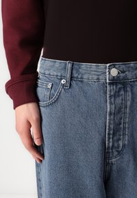 Ljusblå denimjeans med hög midja, med en klassisk femficksdesign, metallknappstängning och subtila bleknade texturdetaijler.